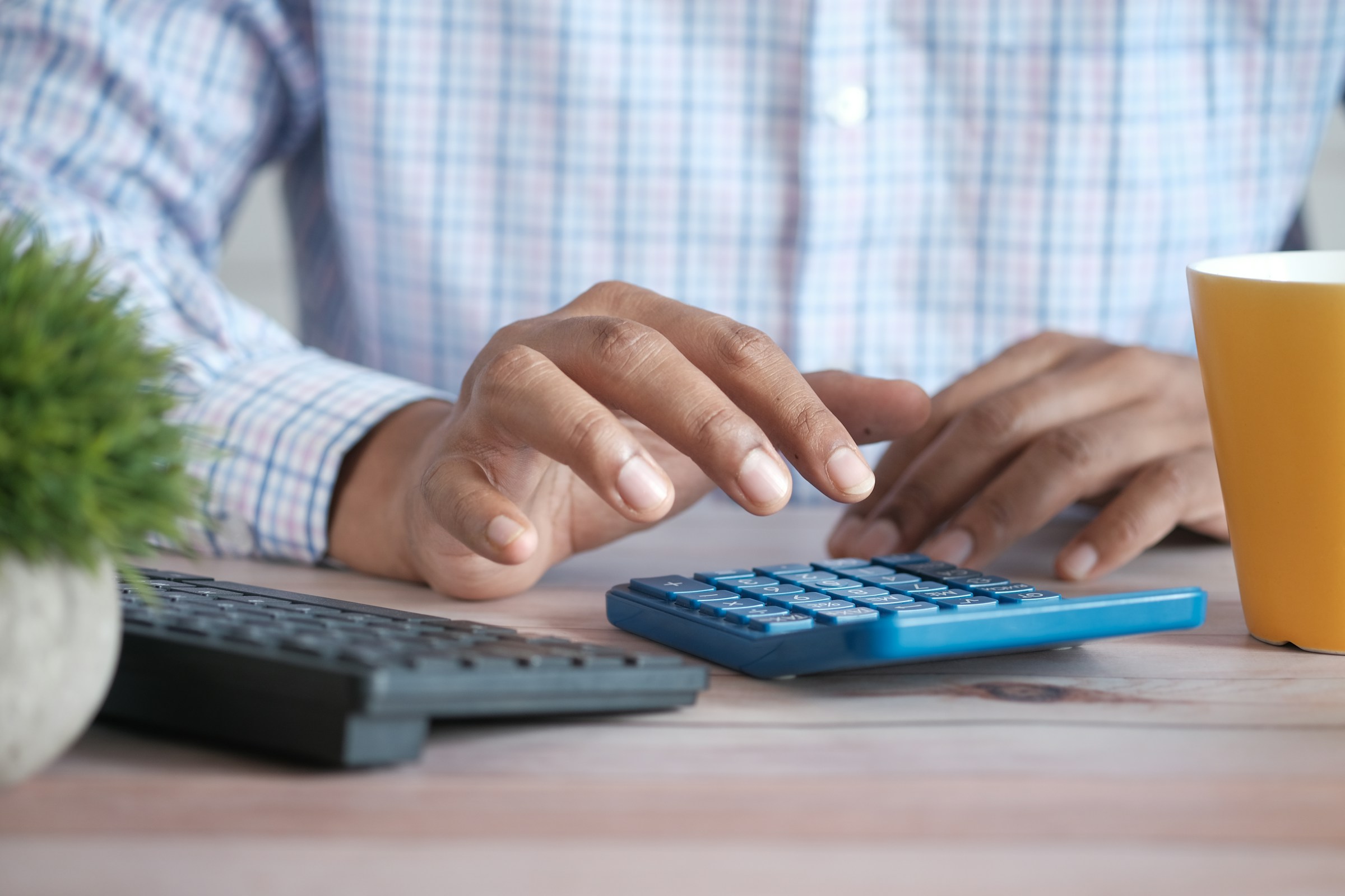 A man in a shirt typing on a calculator