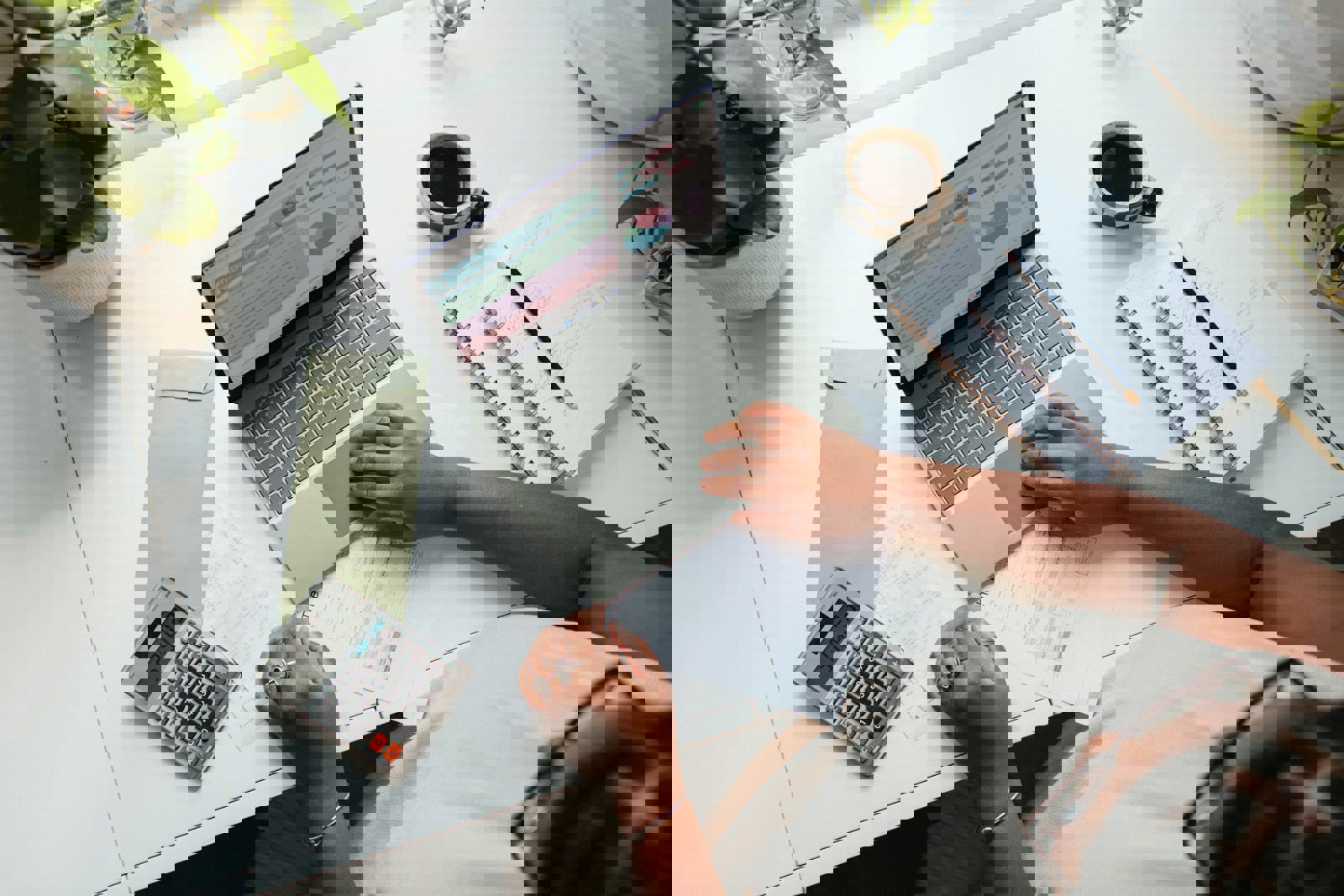 A person working on a laptop next to a calculator