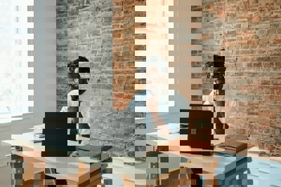 a man sat at a desk looking at a laptop